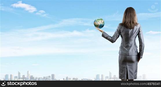 Protect our planet. Back view of businesswoman holding earth planet in hand. Elements of this image are furnished by NASA