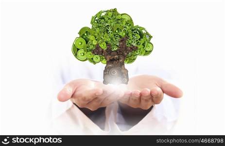 Protect trees and nature. Person holding in palms green tree made of gears