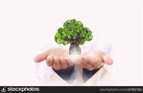 Protect trees and nature. Person holding in palms green tree made of gears