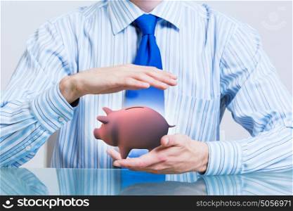 Protect your money savings. Hands of businessman protecting piggy bank with palms