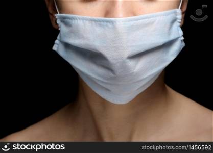 Protection against contagious disease, coronavirus. Female is wearing hygienic face surgical medical mask to prevent infection, respiratory illness as flu, 2019-nCoV. Studio photo black background.. Protection against contagious disease, coronavirus. Female is wearing hygienic face surgical medical mask to prevent infection, respiratory illness as flu, 2019-nCoV. Studio photo black background
