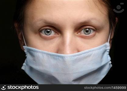 Protection against contagious disease, coronavirus. Female is wearing hygienic face surgical medical mask to prevent infection, respiratory illness as flu, 2019-nCoV. Studio photo black background.. Protection against contagious disease, coronavirus. Female is wearing hygienic face surgical medical mask to prevent infection, respiratory illness as flu, 2019-nCoV. Studio photo black background
