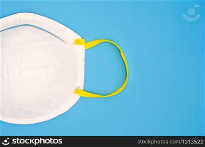 Protective disposable medical mask against coronavirus, flu or influenza on a blue background .. Protective disposable medical mask against coronavirus, flu or influenza on a blue background.
