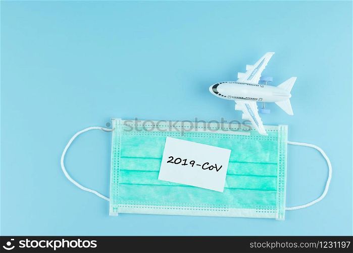 Protective face mask and airplane model on blue background, against Novel coronavirus (2019-nCoV) or Wuhan coronavirus and Influenza. Antiseptic, Hygiene and Healthcare concept