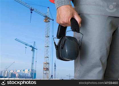 protective headphone at man hands on building background
