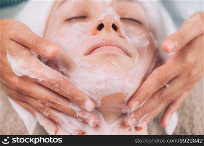 Protein rich facial mask. Cosmetologist applying calming protein mousse onto young woman’s face. . Facial Mousse Mask. Calming Beauty Treatment for Face