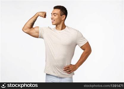 Proud and confident, self-accepting young male athlete, lead active and healthy lifestyle, in good shape, showing muscles, tense arm to brag big strong biceps, smiling pleased, white background.. Proud and confident, self-accepting young male athlete, lead active and healthy lifestyle, in good shape, showing muscles, tense arm to brag big strong biceps, smiling pleased, white background