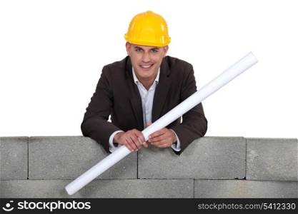 Proud architect stood by wall with rolled-up blueprints