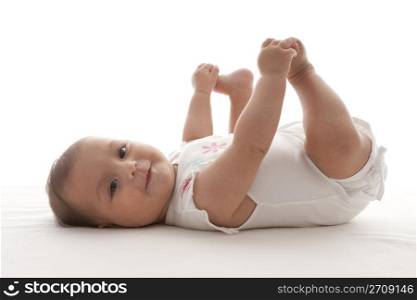 Proud baby girl holding feet lying on her back on the floor