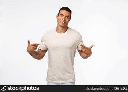 Proud good-looking hispanic muscular young man with tanned skin, tattoos, pointing himself and smiling pleased, praising him, talking personal achievements, suggest to help, white background.. Proud good-looking hispanic muscular young man with tanned skin, tattoos, pointing himself and smiling pleased, praising him, talking personal achievements, suggest to help, white background