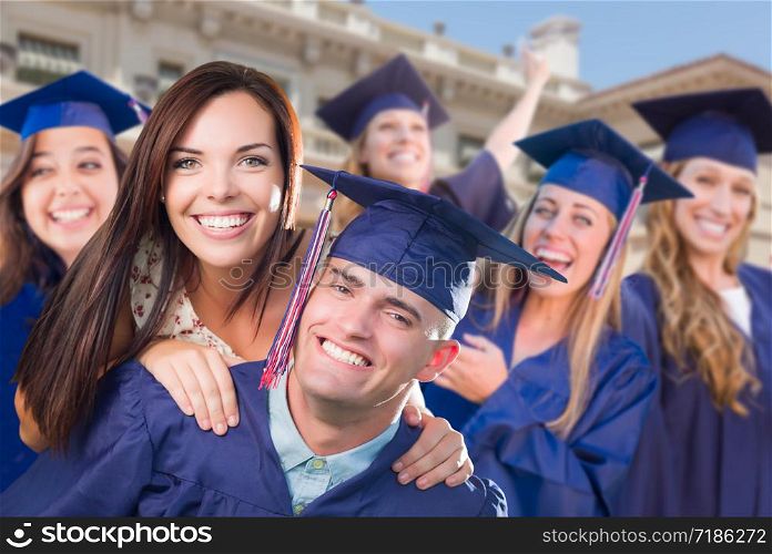 Proud Male Graduate In Cap and Gown with Girl Among Other Graduates Behind.