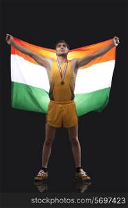 Proud young medalist with Indian flag standing against black background