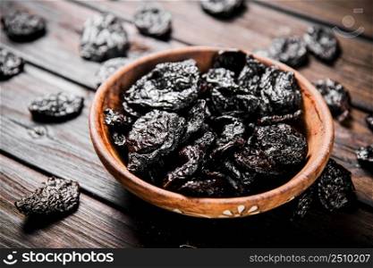 Prunes wooden plate on the table. On a wooden background. High quality photo. Prunes wooden plate on the table.