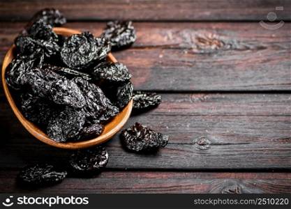 Prunes wooden plate on the table. On a wooden background. High quality photo. Prunes wooden plate on the table.