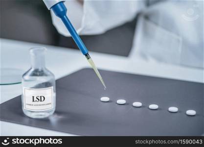 Psychedelic drug LSD therapy research, scientist preparing small doses of LSD in laboratory for an experimental treatment of psychiatric disorders. Psychedelic Drug LSD Therapy Research, Scientist Preparing Small Doses of LSD in Laboratory