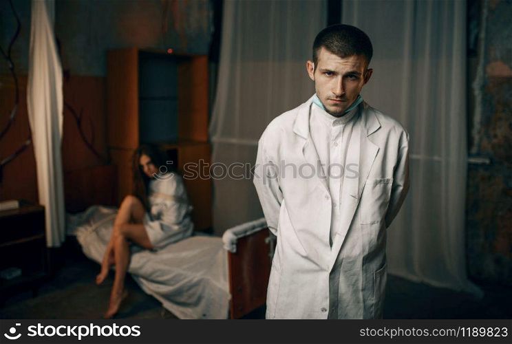 Psychiatrist and crazy female patient in strait jacket, mental hospital. Woman in straitjacket undergoing treatment in clinic for the mentally ill