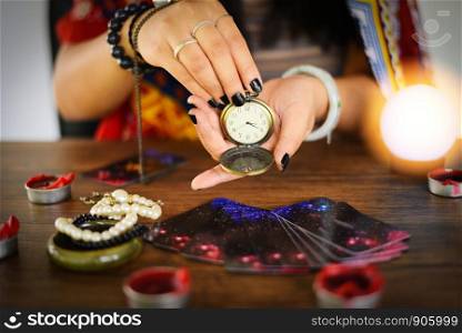 Psychic readings and clairvoyance concept / Crystal ball fortune teller with hands hold retro pocket watch and Tarot cards reading divination