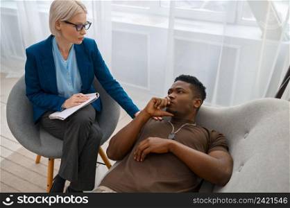 Psychologist giving support to depressed male soldier putting hand on his shoulder. PTSD treatment. Psychologist giving support to depressed male soldier