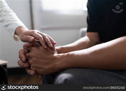 Psychologist woman touching hands to encouraging man with mental health problem in therapy center.