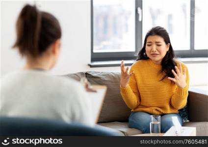 psychology and mental therapy concept - emotional young asian woman patient talking to psychologist at psychotherapy session. woman patient and psychologist at psychotherapy