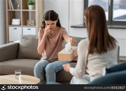 psychology, mental health and people concept - crying woman patient taking paper tissue from psychologist at psychotherapy session. crying woman and psychologist at psychotherapy