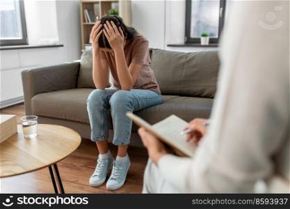 psychology, mental health and people concept - stressed young woman patient and psychologist at psychotherapy session. woman and psychologist at psychotherapy session