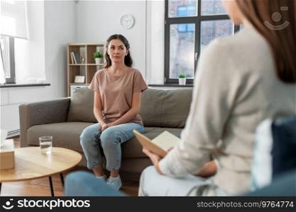 psychology, mental health and people concept - young woman patient and woman psychologist at psychotherapy session. woman and psychologist at psychotherapy session