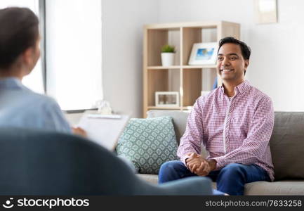 psychology, mental therapy and people concept - happy smiling young indian man patient and woman psychologist at psychotherapy session. man and psychologist at psychotherapy session