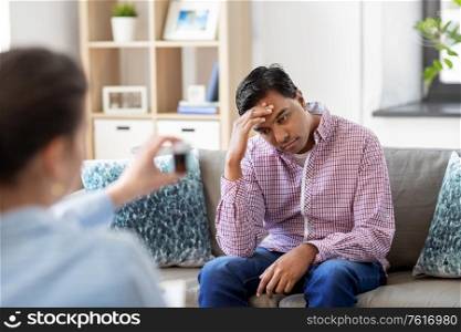 psychology, mental therapy and people concept - stressed young indian man patient and woman psychologist with medicine at psychotherapy session. man and psychologist at psychotherapy session