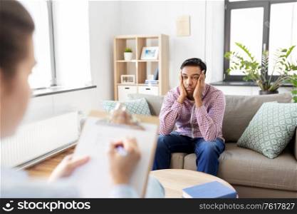 psychology, mental therapy and people concept - stressed young indian man patient and woman psychologist at psychotherapy session. man and psychologist at psychotherapy session