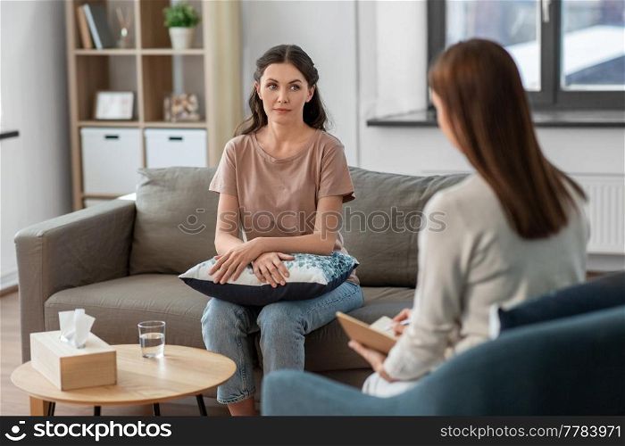 psychology, mental therapy and people concept - young woman patient and woman psychologist at psychotherapy session. woman and psychologist at psychotherapy session