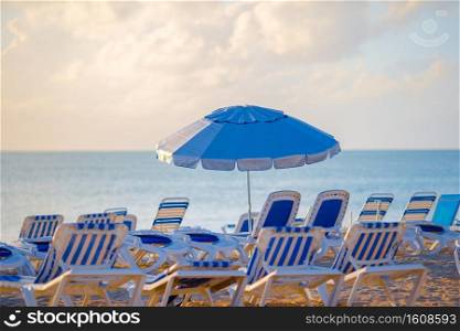 Public beach in a popular resort in the Caribbean. Public beach in a popular resort in the Caribbean with umbrellas and chaise-lounges