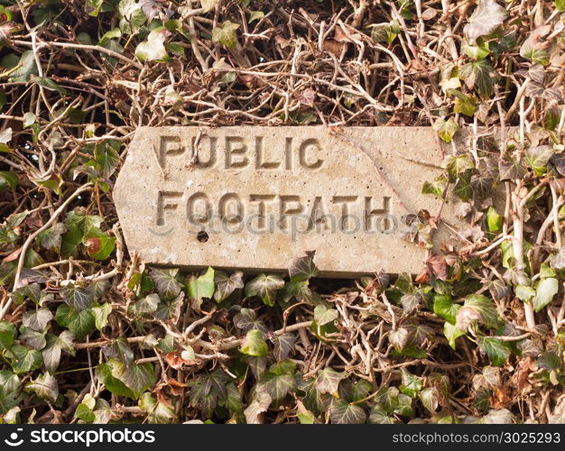 public footpath sign post stone in hedgerow direction pointer; essex; england; uk