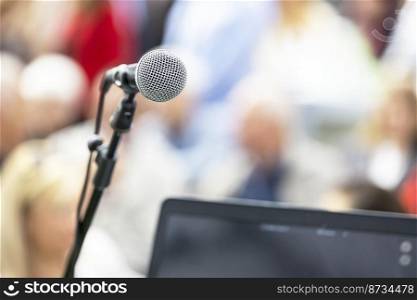 Public speaking event concept, microphone in the focus, blurred people in the background