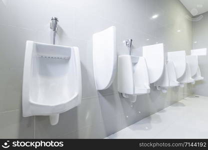 public toilet urinals lined up, no privacy.