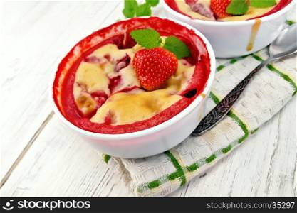 Pudding strawberry in two bowls with berries and mint on a napkin against the background of the wooden planks