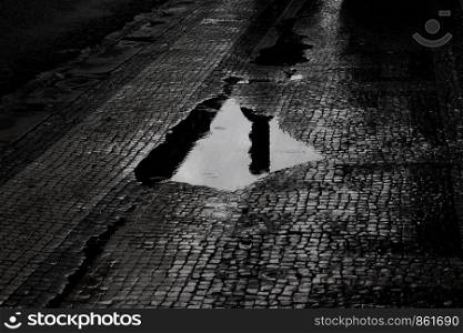 Puddle of water on cobblestone reflects house again