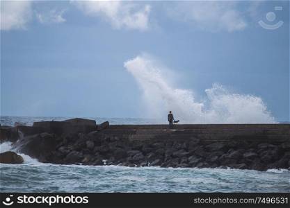 Puerto de la Cruz. fisherman standing on the dock and goes fishing. Big waves
