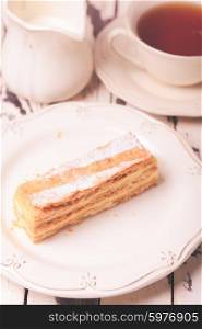 Puff pastry dough with custard cream on a white plate. Sweet piece of Napoleon cake