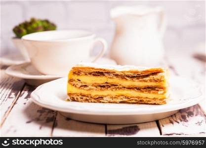 Puff pastry dough with custard cream on a white plate. Sweet piece of Napoleon cake