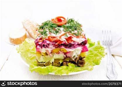 Puff salad with beef, boiled potatoes and beets, pears, spicy carrots, seasoned with mayonnaise and garnished with dill on a green lettuce in a plate, towel, bread on light wooden board background