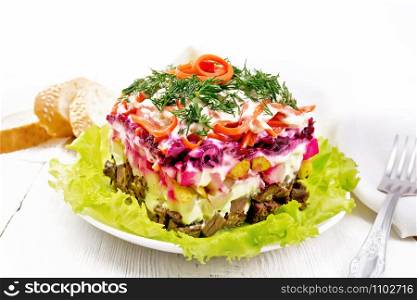 Puff salad with beef, boiled potatoes and beets, pears, spicy Korean carrots, seasoned with mayonnaise and garnished with dill on a green lettuce in a plate, napkin, bread on light wooden board background