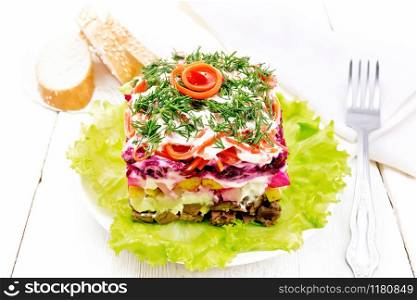 Puff salad with beef, boiled potatoes and beets, pears, spicy Korean carrots, seasoned with mayonnaise and garnished with dill on a green lettuce in a plate, towel, bread on wooden board background