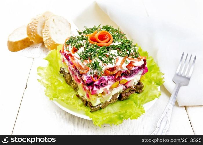 Puff salad with beef, boiled potatoes and beets, pears, spicy Korean carrots, seasoned with mayonnaise and garnished with dill on a green lettuce in a plate, napkin, bread on wooden board background
