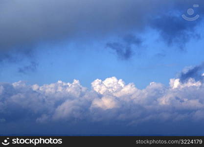 Puffy White Clouds With Dark Clouds In A Light Blue Sky