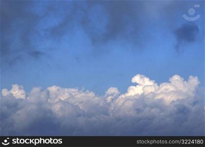 Puffy White Clouds With Dark Clouds In A Light Blue Sky