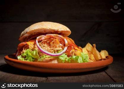 Pulled Pork Burger with lettuce, cheese, onion and barbecue Sauce, served on a rustic plate on wooden table. High quality photography.. Pulled Pork Burger with lettuce, cheese, onion and barbecue Sauce, served on a rustic plate on wooden table.