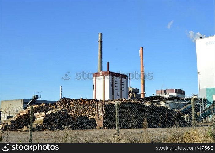 Pulp mill with two fireplaces, wood and a blue sky