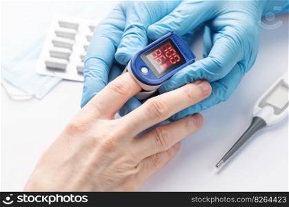 Pulse oximeter measuring oxygen saturation in blood and heart rate.  Pulse oximeter on the patient’s hand