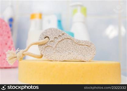 Pumice stone in foot shape on yellow bath sponge. Bathroom objects. Pedicure essentials.. Pumice stone in foot shape